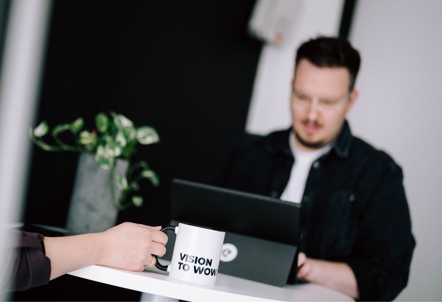 Suchmaschinenoptimierung -faktoren Ein Mann sitzt an einem Tisch mit einem Laptop und einer Kaffeetasse, während er an Suchmaschinenoptimierung arbeitet.