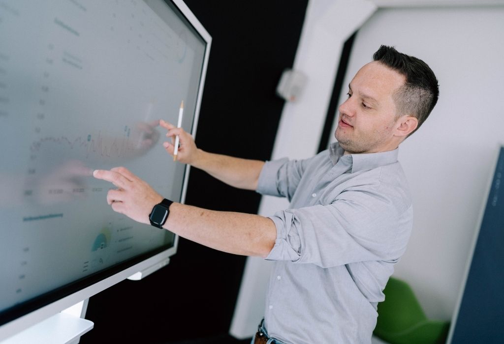 webentwicklung Ein Mann interagiert mit einem großen Bildschirm, um wichtige Daten zur Webentwicklung zu analysieren.
